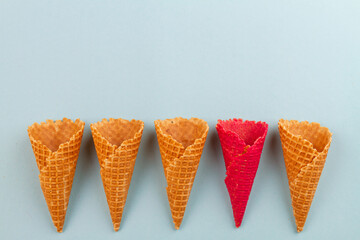Red ice cream cone waffle amoung ordinary ones. Blue pastel background.