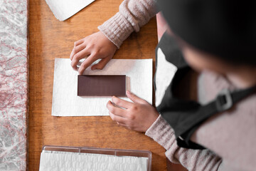 Female confectioner wrapping chocolate in paper