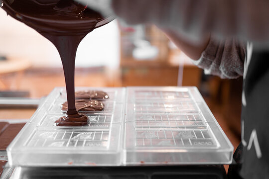 Anonymous worker confectioner pouring chocolate into mold