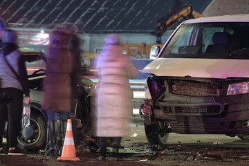 Cars crashed heavily in road accident after collision and silhouette of people on city street at...