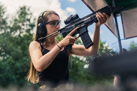 young woman practicing shooting on target and holding a black rifle, medium shot. High quality photo