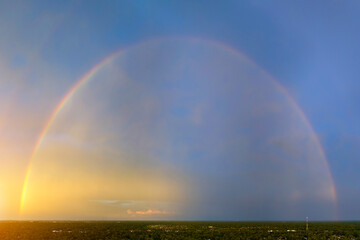 Colorful round rainbow against blue evening sky after heavy thunderstorm