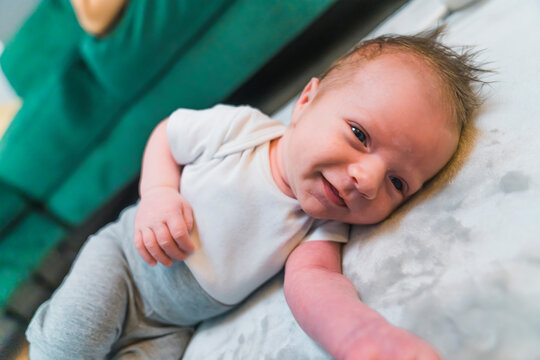 Child development concept. Amused little caucasian infant baby spreading his arm towards the camera and smiling. Casual baby clothing. High quality photo