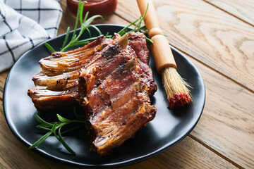 Grilled and smoked pork ribs with barbeque sauce on an old vintage wooden cutting board on old wooden table background. Tasty snack to beer. American food concept. Top view.