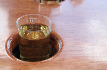 Small glass filled with wine in a fitting hole in the table