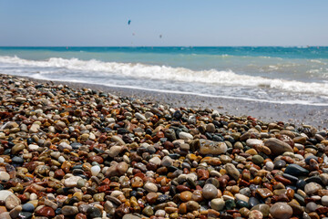 Beach with colorful wet pebbles and wavy sea