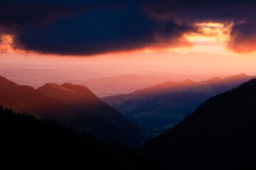 Fototapeta premium dramatic sunset with clouds and the sun in the Alpine foothills of Fribourg