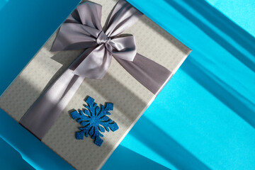 Fototapeta premium Gray gift box with bow and snowflake on blue background