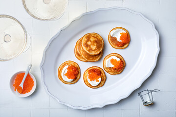 Festive appetizer with champagne glass. Mini Blini pancakes with sour cream and red caviar. Gourmet party food