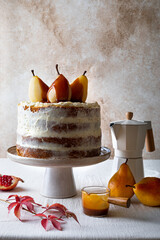Fall ginger cake decorated with spicy poached pears and caramel sauce. Creamy naked cake on cake stand.