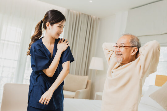 female physiotherapist helping senior man exercise, helping elderly male patient on bed in morning 