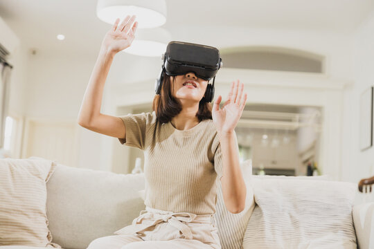 woman wearing VR and playing game on sofa at home