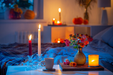 cup of tea and  chrysanthemum in vase with burning candles in bedroom