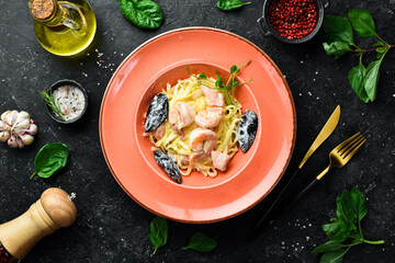 Seafood. Pasta with shrimp, mussels, cheese and basil in a plate. Italian dish. On a black stone background.