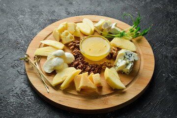 Cheese slice. Hard cheese, blue cheese and brie. On a black stone background.