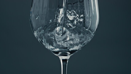 Sparkling water pouring glass at dark background closeup. Air bubbles rising