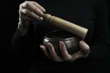 Tibetan singing bowl in a woman's hands. Photographed in the studio. Artificial lighting.