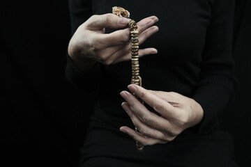 The woman has prayer beads in her hands. Photographed in the studio. Artificial lighting.