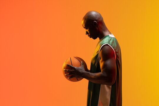 Image of african american basketball player with basketball on neon orange background