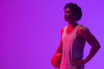 Image of biracial basketball player with basketball and copy space on neon purple background