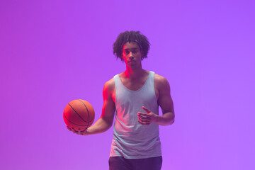 Image of biracial basketball player with basketball on neon purple background