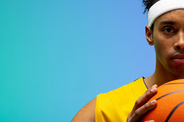 Image of portrait of biracial basketball player with basketball with copy space on blue background