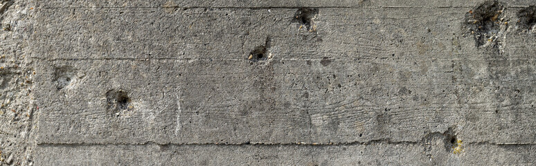 Wide concrete wall with bullet holes background. Bullet holes on a gray concrete wall of a second world war bunker in Normandy - obrazy, fototapety, plakaty