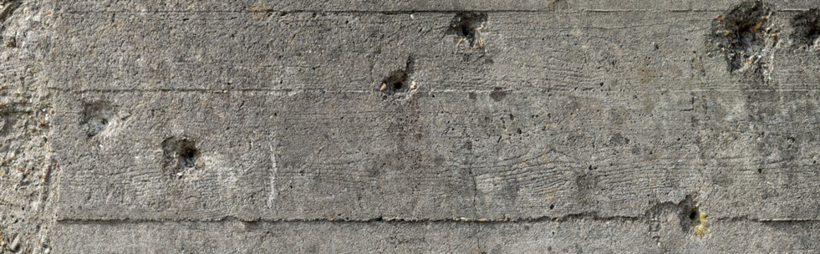 Wide concrete wall with bullet holes background. Bullet holes on a gray concrete wall of a second world war bunker in Normandy