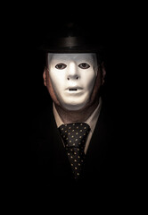Portrait of a man with a white mask and bowler hat on a black background