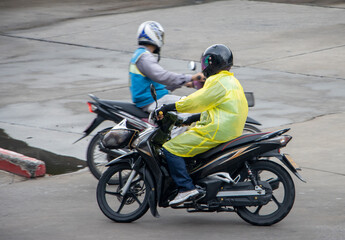 The moto taxi drivers ride on a wet road, Thailand