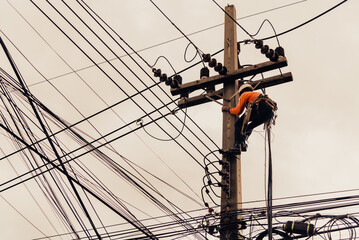 Asian electricians are climbing on electric poles to install and repair power lines.
