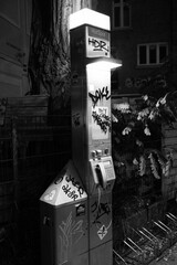 Vertical grayscale view of a dirty old public telephone booth in Hamburg