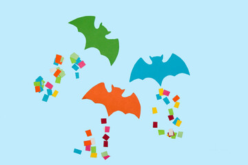 colorful bats on a blue background leaving a colorful trail behind, creative halloween concept, flat lay paper craft
