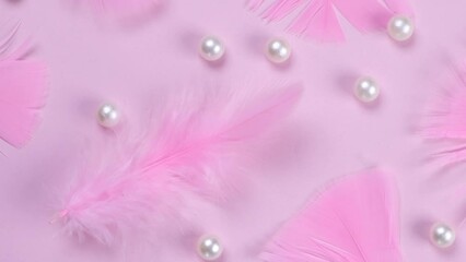 Rotating pink feathers on a pink background with pearls, a fashionable, decorative, delicate, feminine background. the concept of a party or birthday in pink colors, or a newborn girl