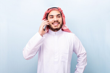 Young arabian, smiling with traditional wear, using the mobile phone.