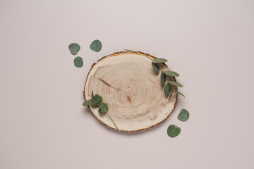 Wooden podium on light background with  green eucalyptus leaves. Top view  showcase, product,...