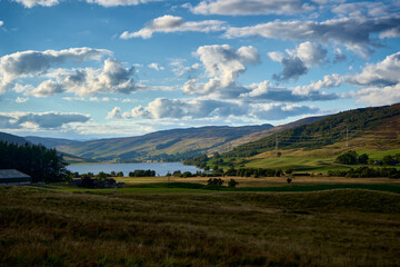 Glen Quaich -  Scottish glen with a loch and green fields and forest under colorful sky