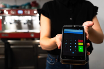 close-up of an unrecognizable waitress holding the card payment device. card payment method in a bar, restaurant or coffee shop.