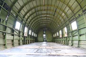 Fuselage of the inside of a military green plane during the war era showing the empty space that troops were carried in. Paratroopers would jump from this plane and sky dive to the ground