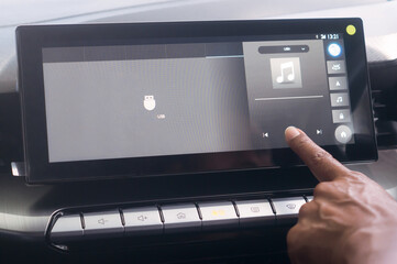 Close up photo, driiver's forefinger touching flat screen player to turn on music while driving super modern car, Concept of using high technology accessories in modern car in vintage color tone. - obrazy, fototapety, plakaty
