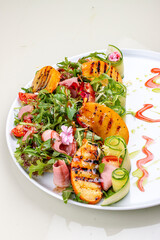 Fresh salad with ham and arugula, with grilled persimmon.
