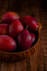 Fototapeta na wymiar Brown bowl with fresh organic purple plums on a wooden table. Fresh organic fruits. Harvest time.