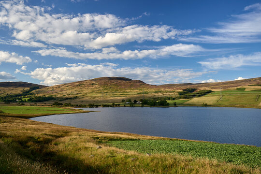 Scotland's Glen Quaich has a lake, lush farmland, and a woodland beneath a brilliant sky. © Valentine