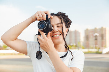 A young photographer with a professional outdoor camera. Space for text. a girl with dreadlocks photographs the city landscape. photo.