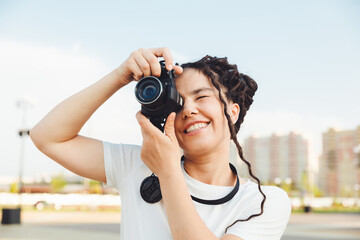 A young photographer with a professional outdoor camera. Space for text. a girl with dreadlocks photographs the city landscape. photo.