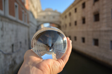 Hand holding glass sphere in front of ponte dei sospiri - bridge of sighs