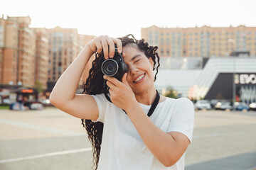 A young photographer with a professional outdoor camera. Space for text. a girl with dreadlocks photographs the city landscape. photo.