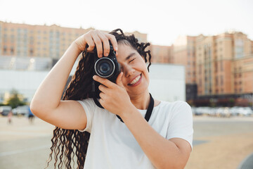 A young photographer with a professional outdoor camera. Space for text. a girl with dreadlocks photographs the city landscape. photo.