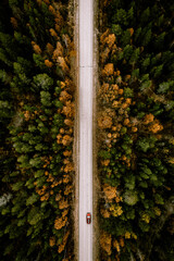 Aerial view of fall road with autumn woods and first snow in Finland.