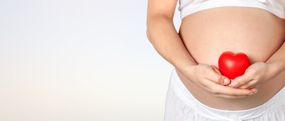women with red heart on her belly. Pregnancy concept